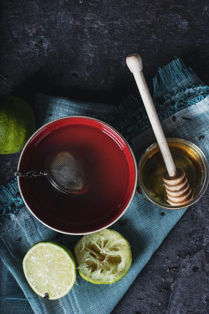 red ceramic bowl filled with water beside lime and honey