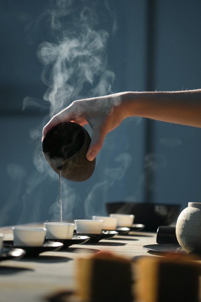 person pouring hot water in a tea cup